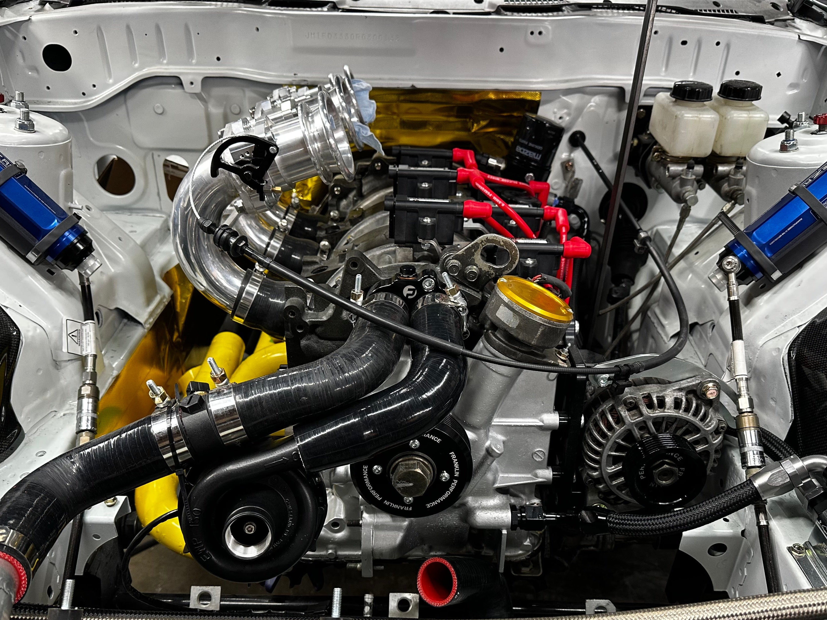 Car engine with various components and hoses in a close-up view.